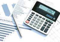 A calculator and pen on top of financial reports. Focus on displayed digits.